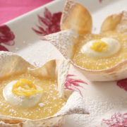 orange-and-lemon-curd-tarts-in-mountain-bread-base-served-with-a-dollop-of-cream-and-dusted-with-icing-sugar.