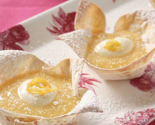 orange-and-lemon-curd-tarts-in-mountain-bread-base-served-with-a-dollop-of-cream-and-dusted-with-icing-sugar.